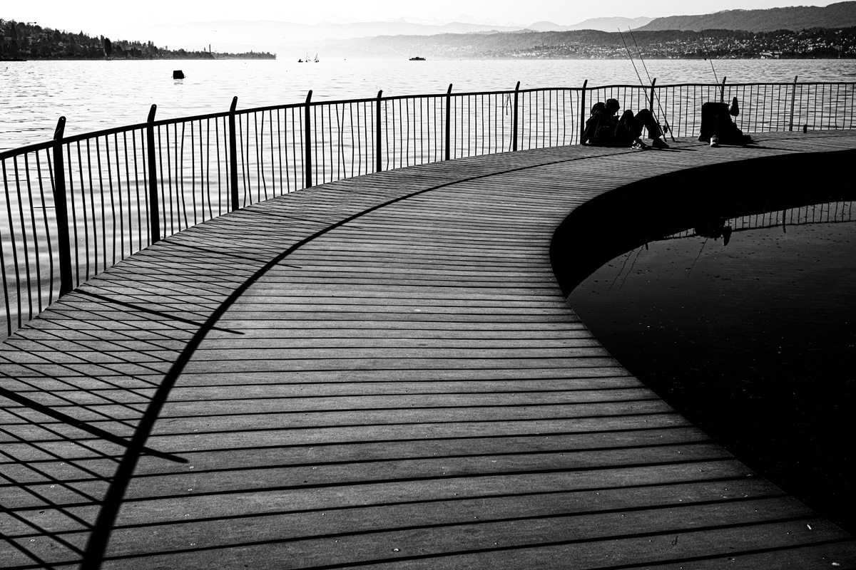 two-men-sitting-and fishing-on-footbridge