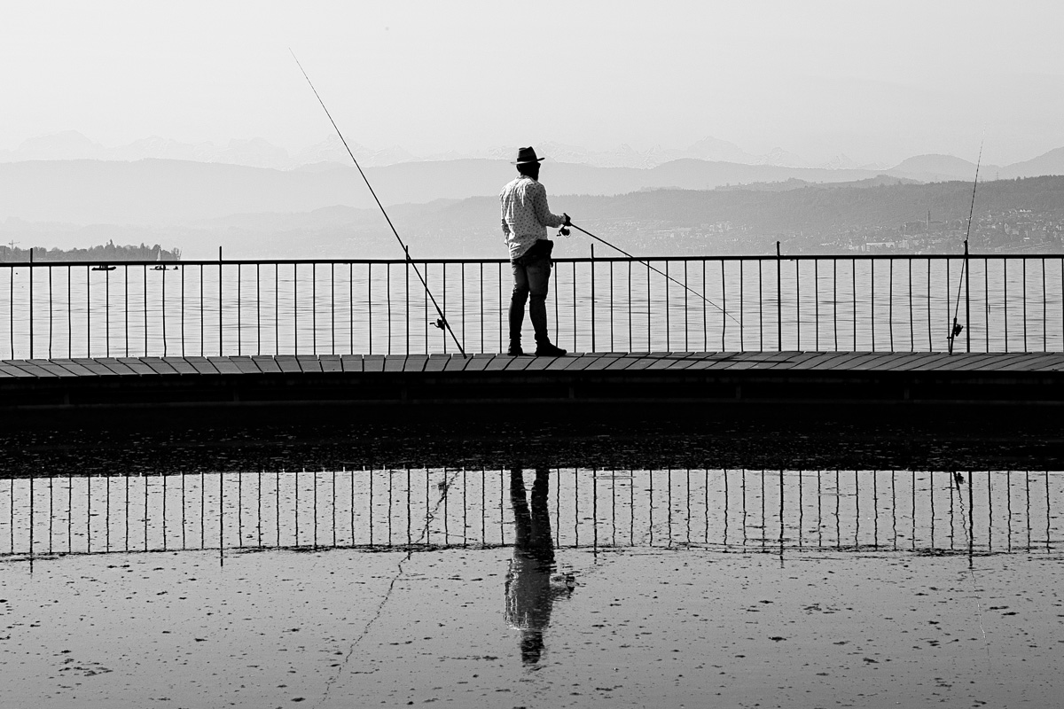 man-fishing-panoramic-view-against-lake